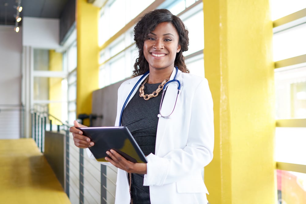 Portrait of a female doctor holding her patient chart on digital tablet in bright modern hospital Portrait of a female doctor holding her patient chart on digital tablet in bright modern hospital