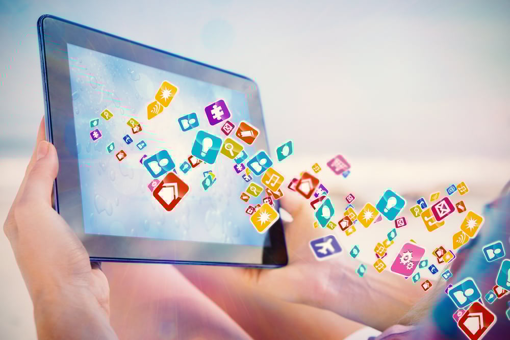 Woman sitting on beach in deck chair using tablet pc showing colourful computer applications